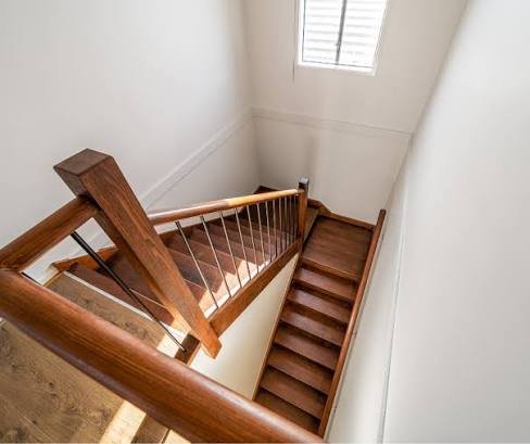 Dark stained wooden handrail with vertical metal rod balusters on switchback stairs Dark stained wooden handrail with vertical metal rod balusters on switchback stairs