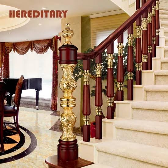 Ornate carved wooden staircase with gold metal balusters and decorative newel post Ornate carved wooden staircase with gold metal balusters and decorative newel post